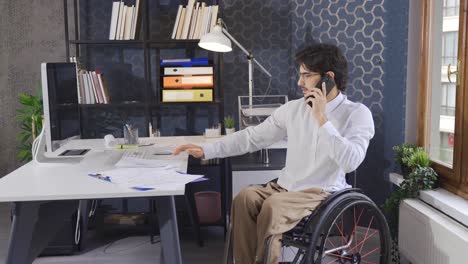 Office-worker-disabled-businessman-talks-by-phone-and-works-with-computer.